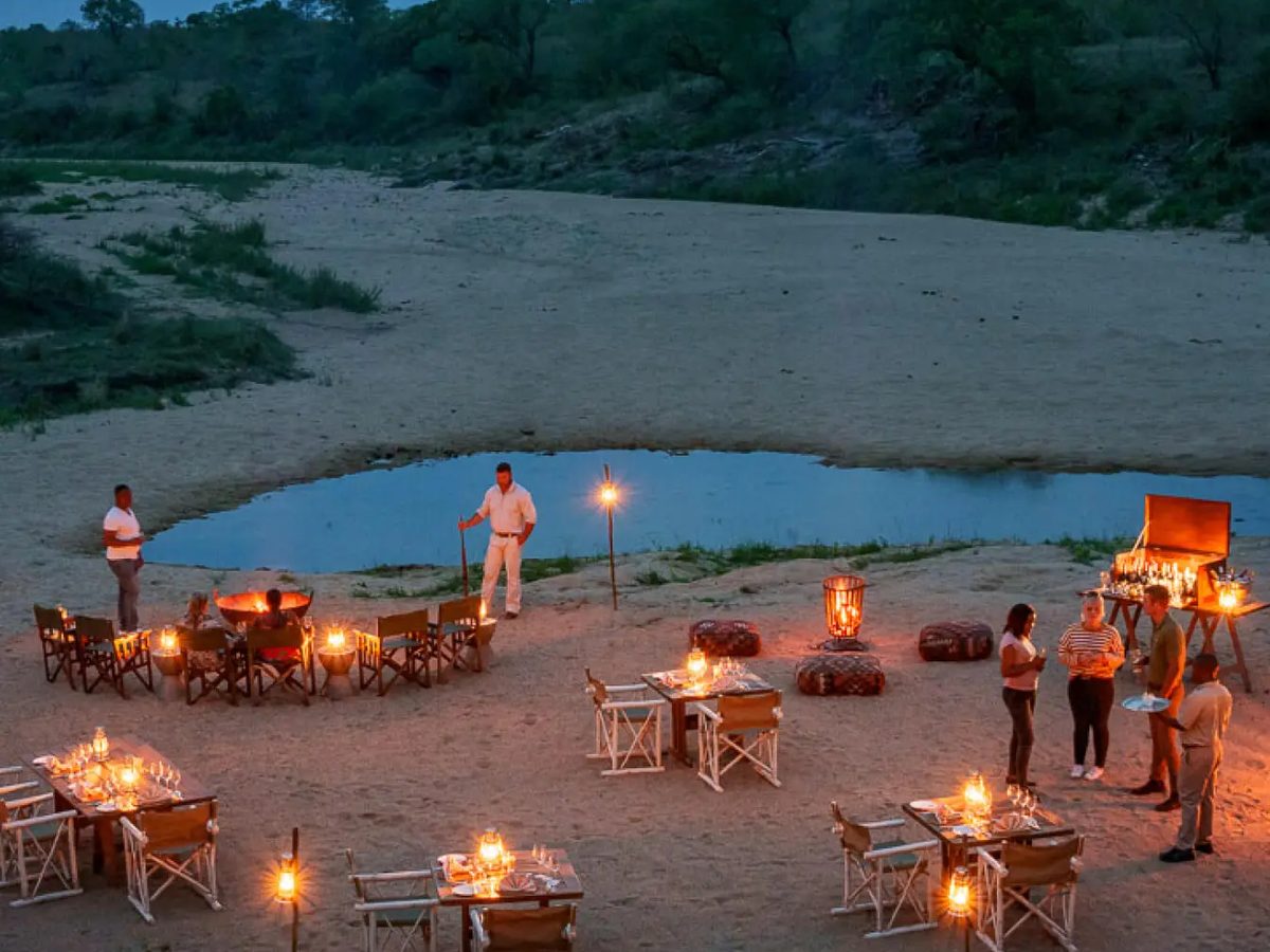 Lantern-lit dinner set out in the dry riverbed at Jock Safari Lodge