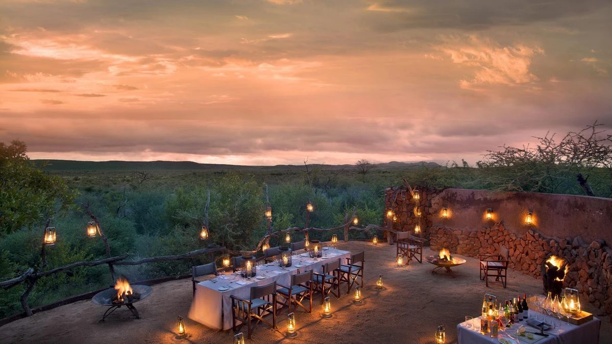 Boma dinner table lit by lanterns at dusk at Madikwe Safari Lodge