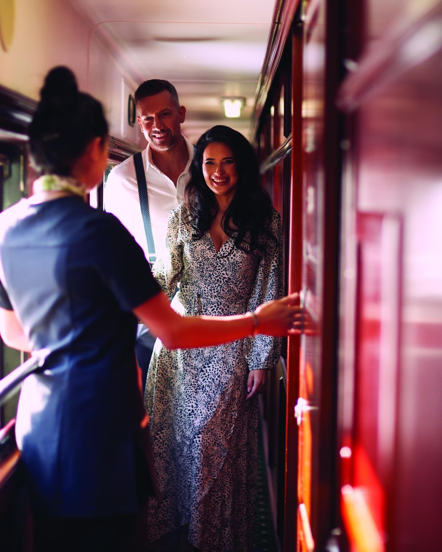 A Rovos Rail hostess welcoming two guests aboard at the carriage door