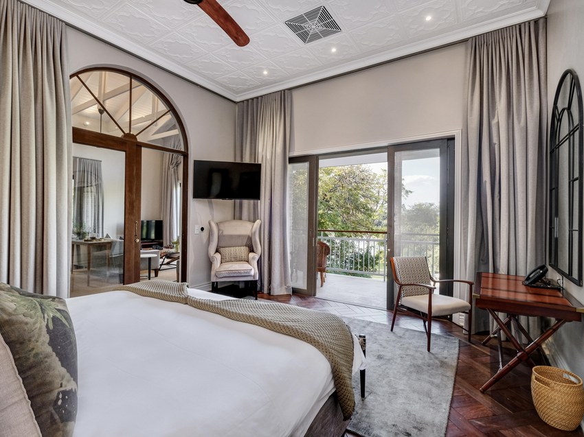 A room at the Palm River Hotel with an arched window, a bed and doors opening onto a terrace