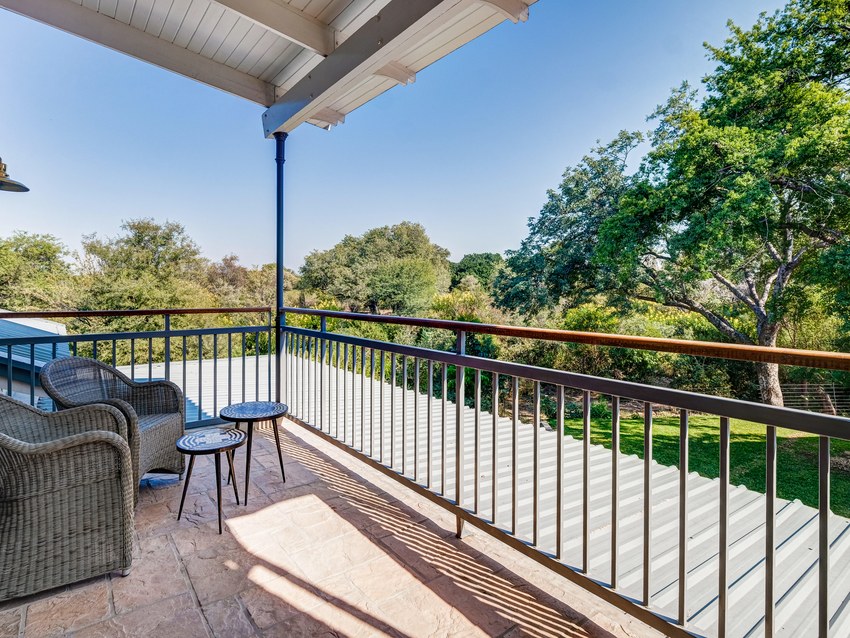A private balcony at the Palm River Hotel with wicker chairs, looking out over trees towards the river