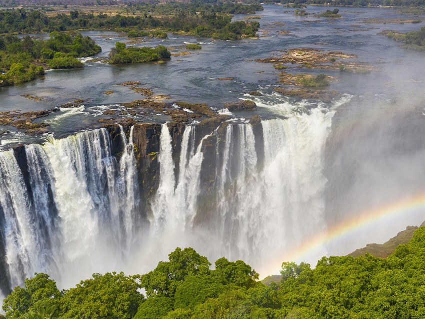 Victoria Falls in full flow seen from above with a rainbow in the spray