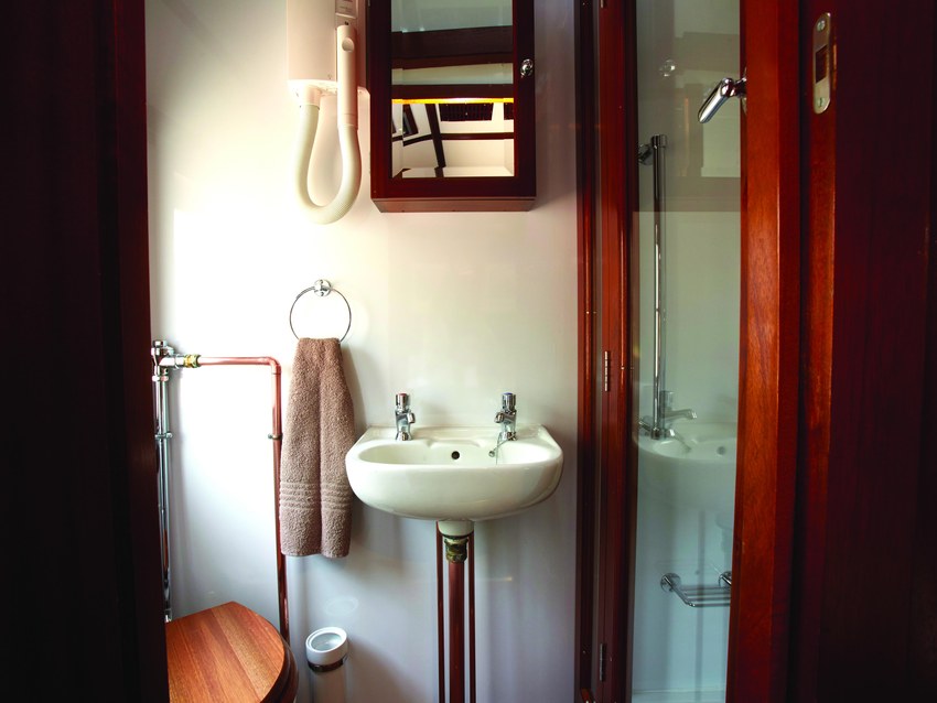 The compact en-suite bathroom of a Rovos Rail suite with a basin, mirror and shower