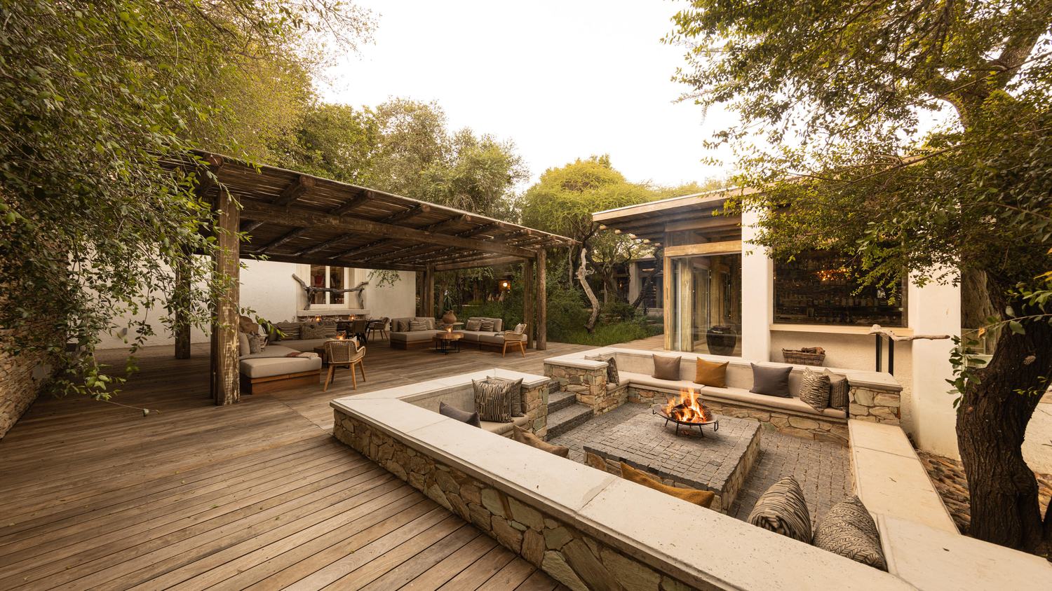 The open-sided deck and lounge area at Kapama Karula Lodge, with a sunken fire pit and seating overlooking the bush