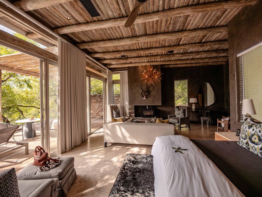 The bedroom of a Superior Luxury Villa at Kapama Karula, with a canopied bed and glass doors opening onto the deck