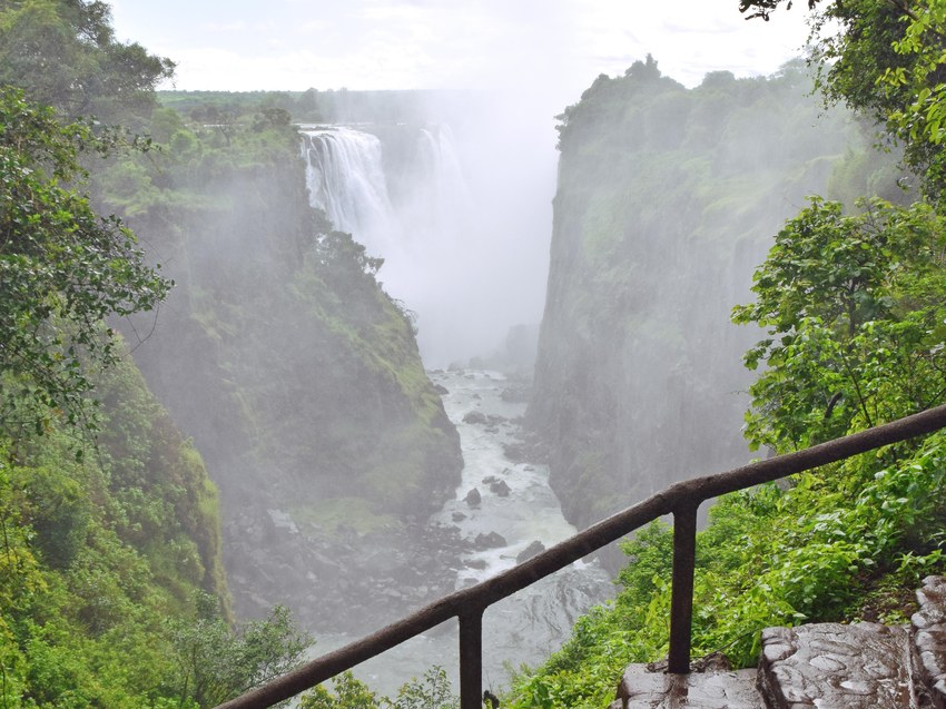 A railed viewpoint on the rainforest path at Victoria Falls looking across the gorge towards the spray