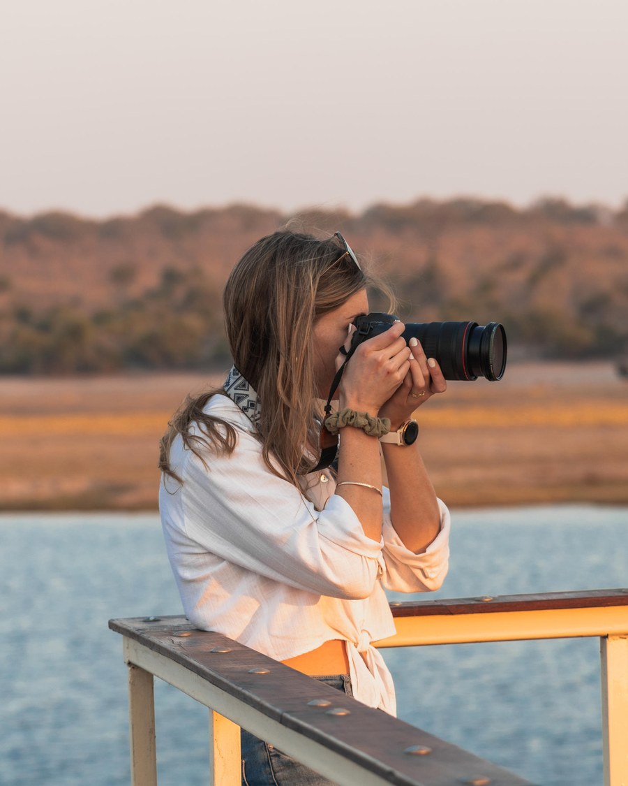 A guest photographing wildlife from the rail of the Chobe Princess houseboat on the Chobe River