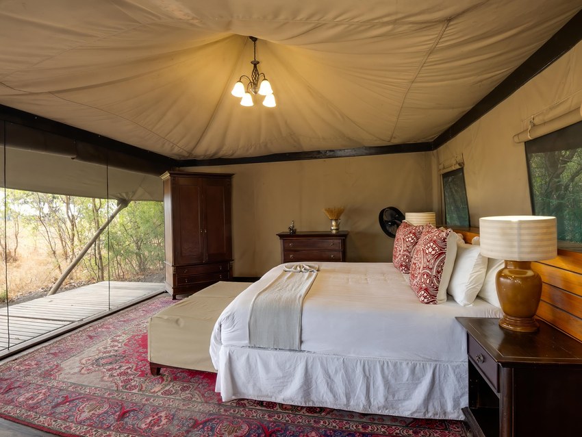 The interior of a tent at Kadizora Camp with a large bed, rugs and a canvas ceiling
