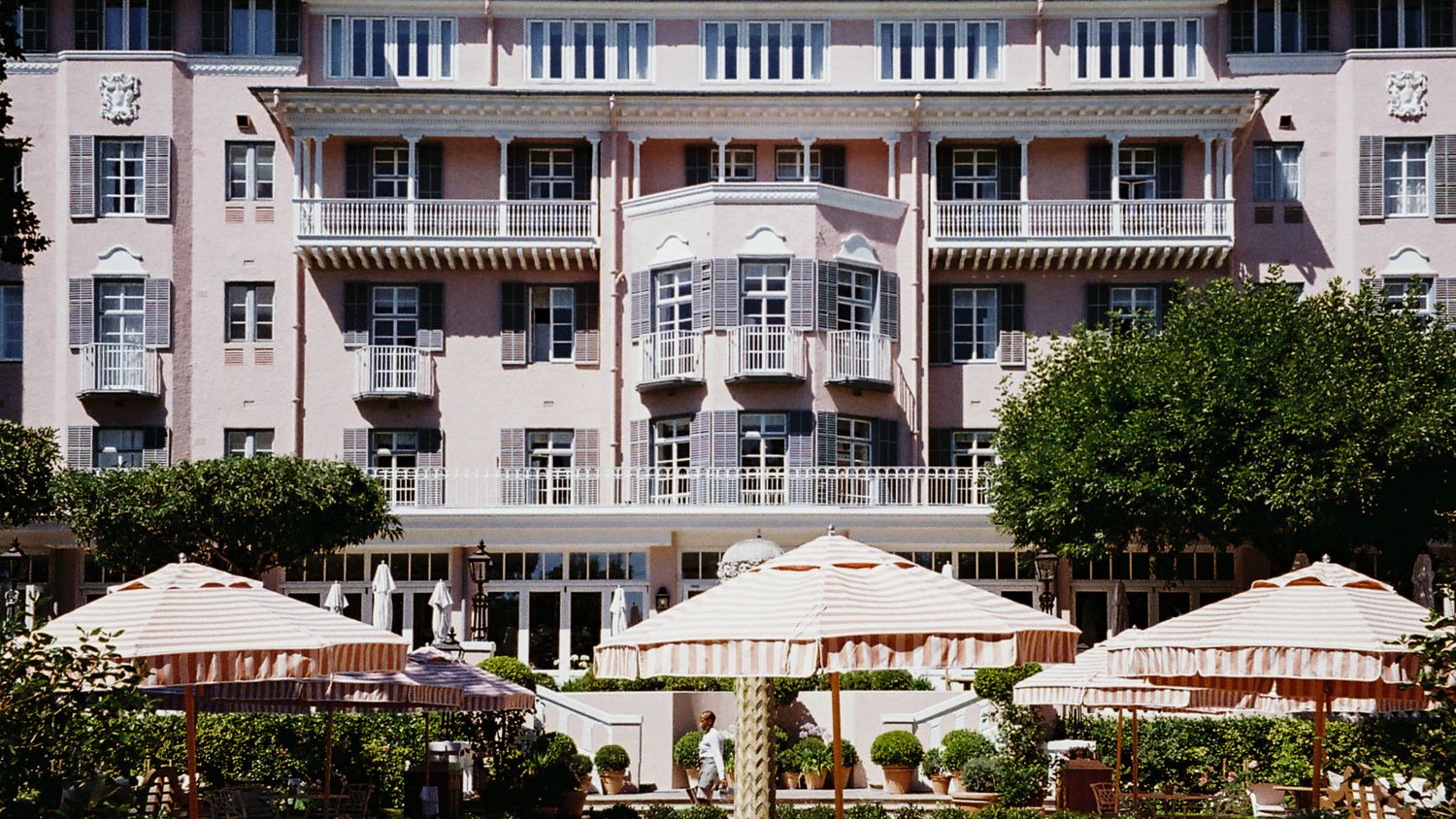 The pink facade of the Mount Nelson hotel in Cape Town with striped umbrellas on the terrace below