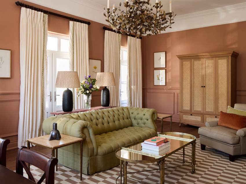 A sitting room at the Mount Nelson with a green velvet sofa, armchairs and a chandelier