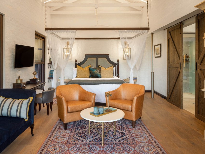 A Deluxe King suite at Mbano Manor with a king bed, lounge chairs and a writing desk