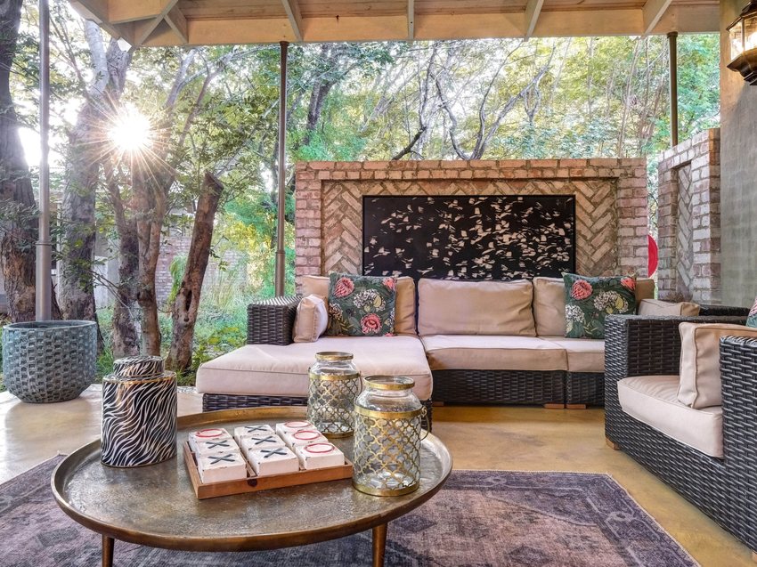 An open-sided lounge at Mbano Manor with a fireplace and seating under the trees