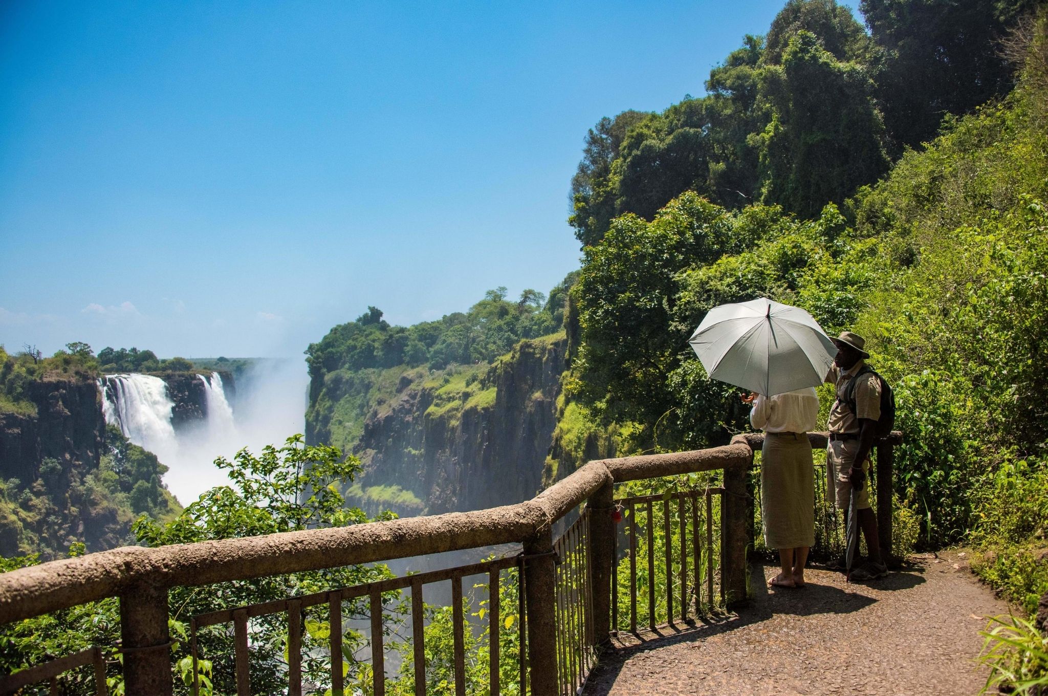 Tourists standing at a viewing point overlooking Victoria Falls during moderate water season.